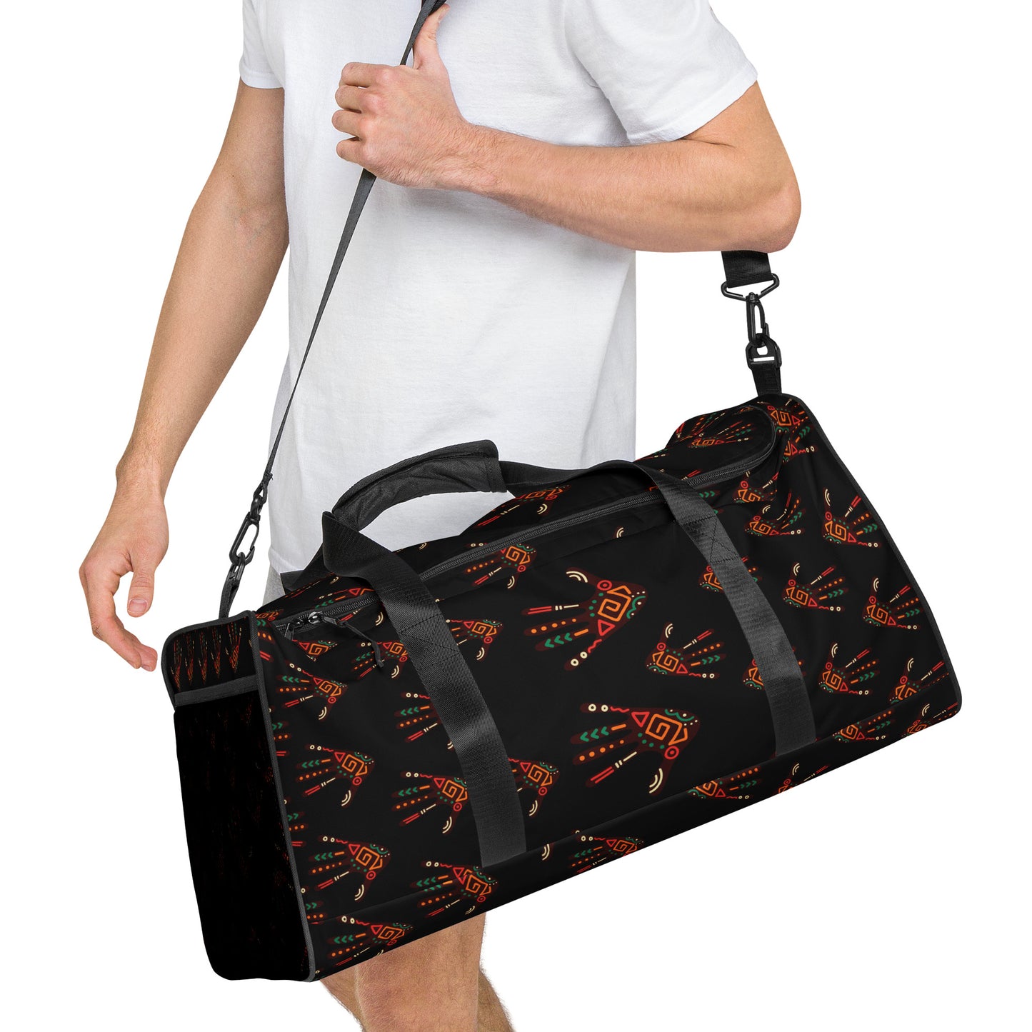 Man carrying red colored Duro Duffle Bag by the long padded shoulder strap; showing the custom tribal palm print design on a black background, dual padded handles, and a mesh side pocket.