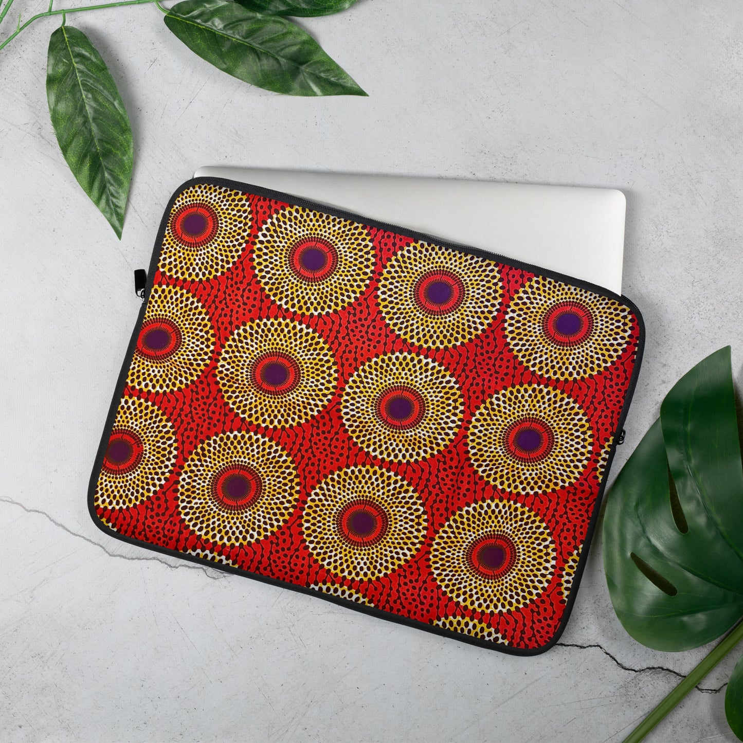 A vibrant 15 inch laptop sleeve with an African print design, featuring a top-loading zippered enclosure and two sliders, placed on a flat surface with a laptop inside.