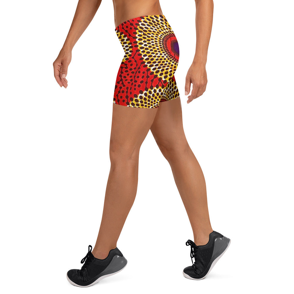 Side view of woman in sneakers wearing vibrant colored, geometric-pattern Rekiana African print athleisure sport shorts