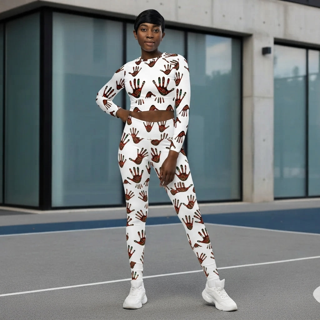 A model wearing a matching white two-piece activewear set with a brown handprint pattern, standing on an outdoor court in front of a modern glass building.