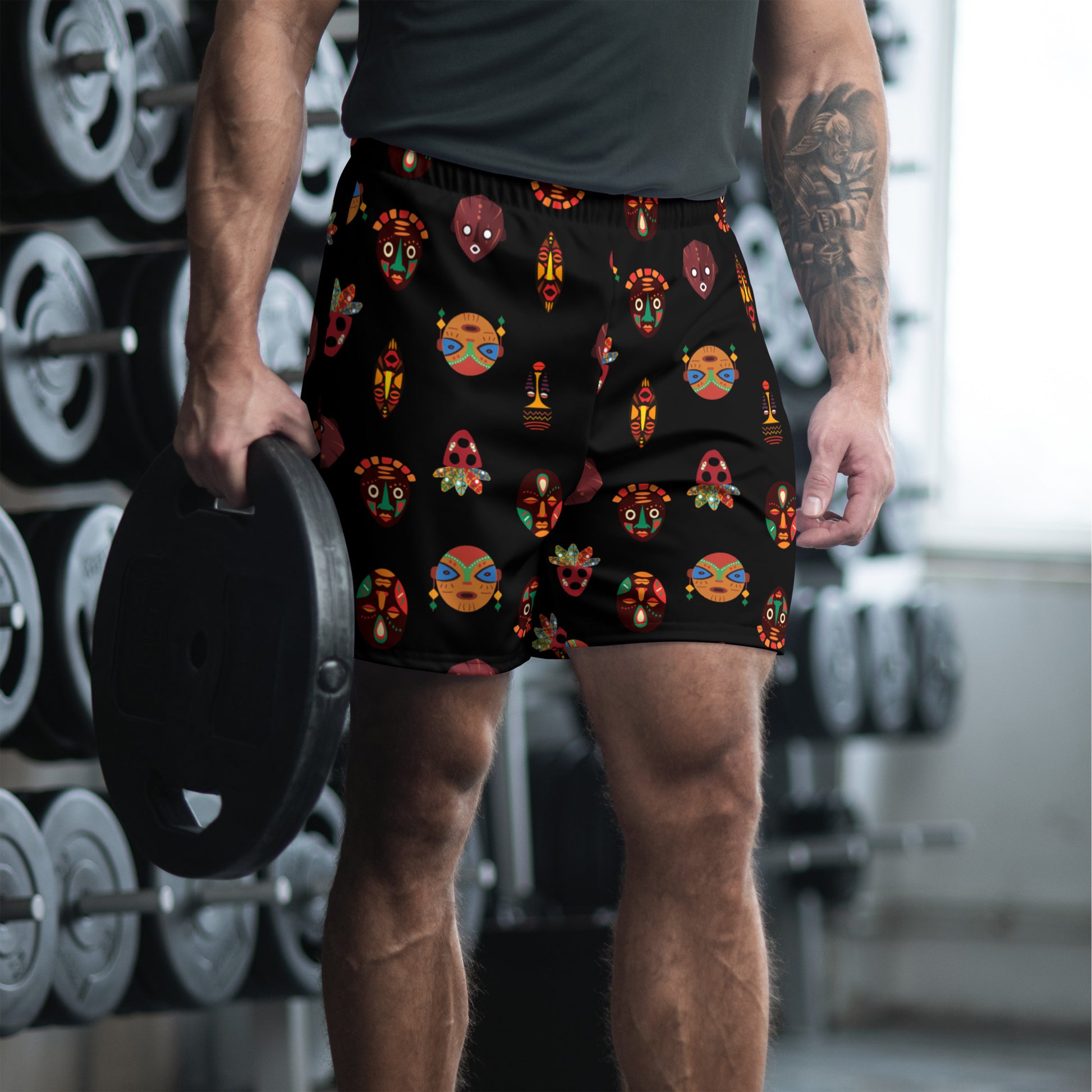 A man wearing black athletic shorts with a vibrant tribal mask print.