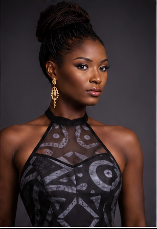 Woman wearing a black patterned dress with gold earrings against a dark background