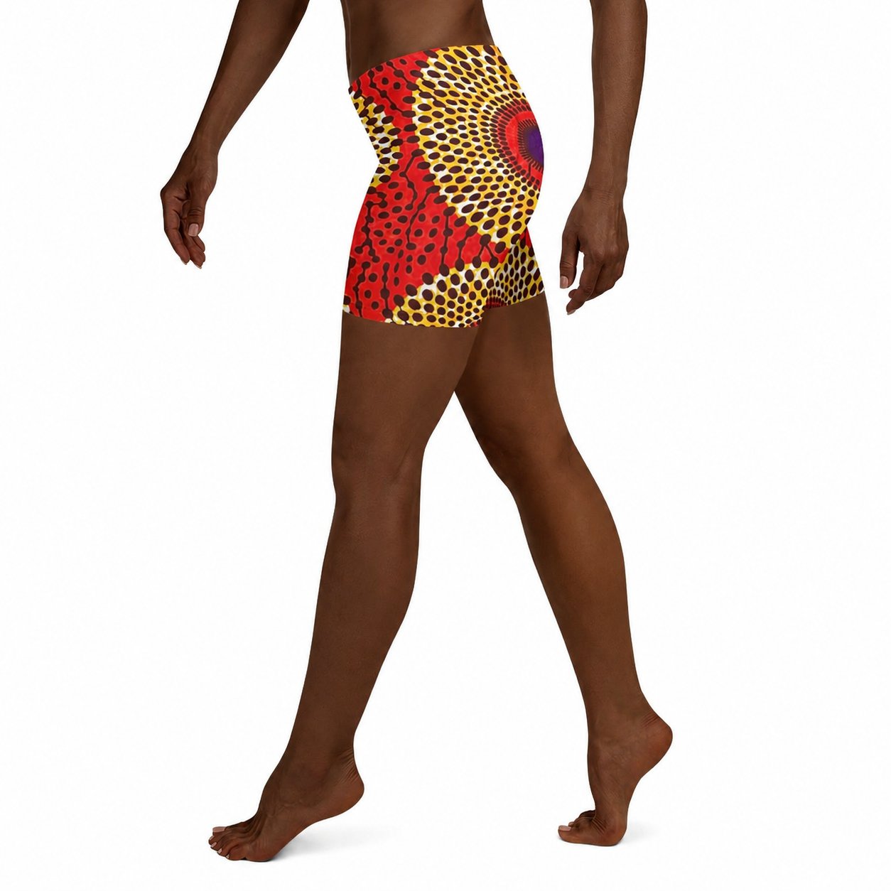 A person wearing high-waisted athletic shorts with a bold African wax print pattern in red, yellow, black, and purple, shown from a side/back angle against a white background.