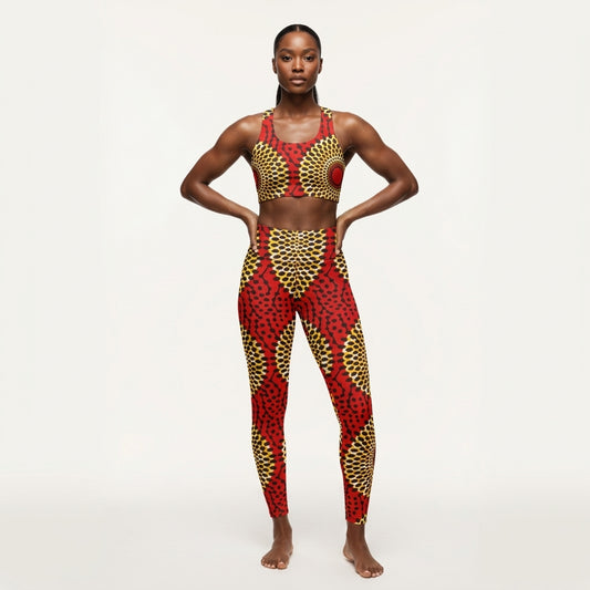 A woman modeling asake oge matching two-piece activewear set featuring a red and gold patterned sports bra and high-waisted leggings, posed against a solid off-white studio background.