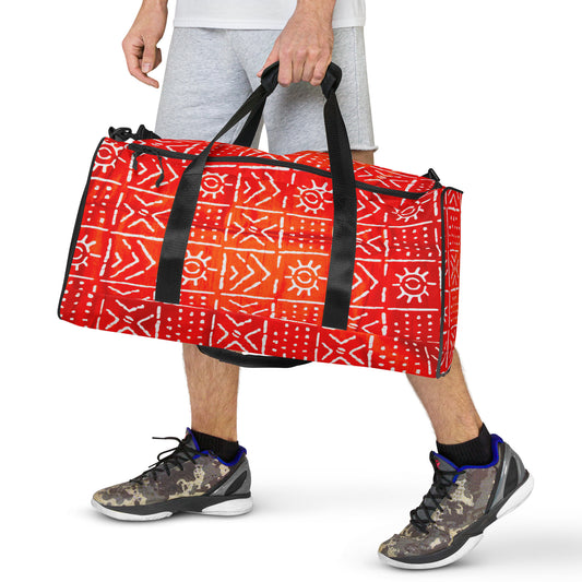 A man holding the Aquila Print Duffle Bag by hand, with its dual shorter straps; showing the front view of geometric tribal pattern designs upclose