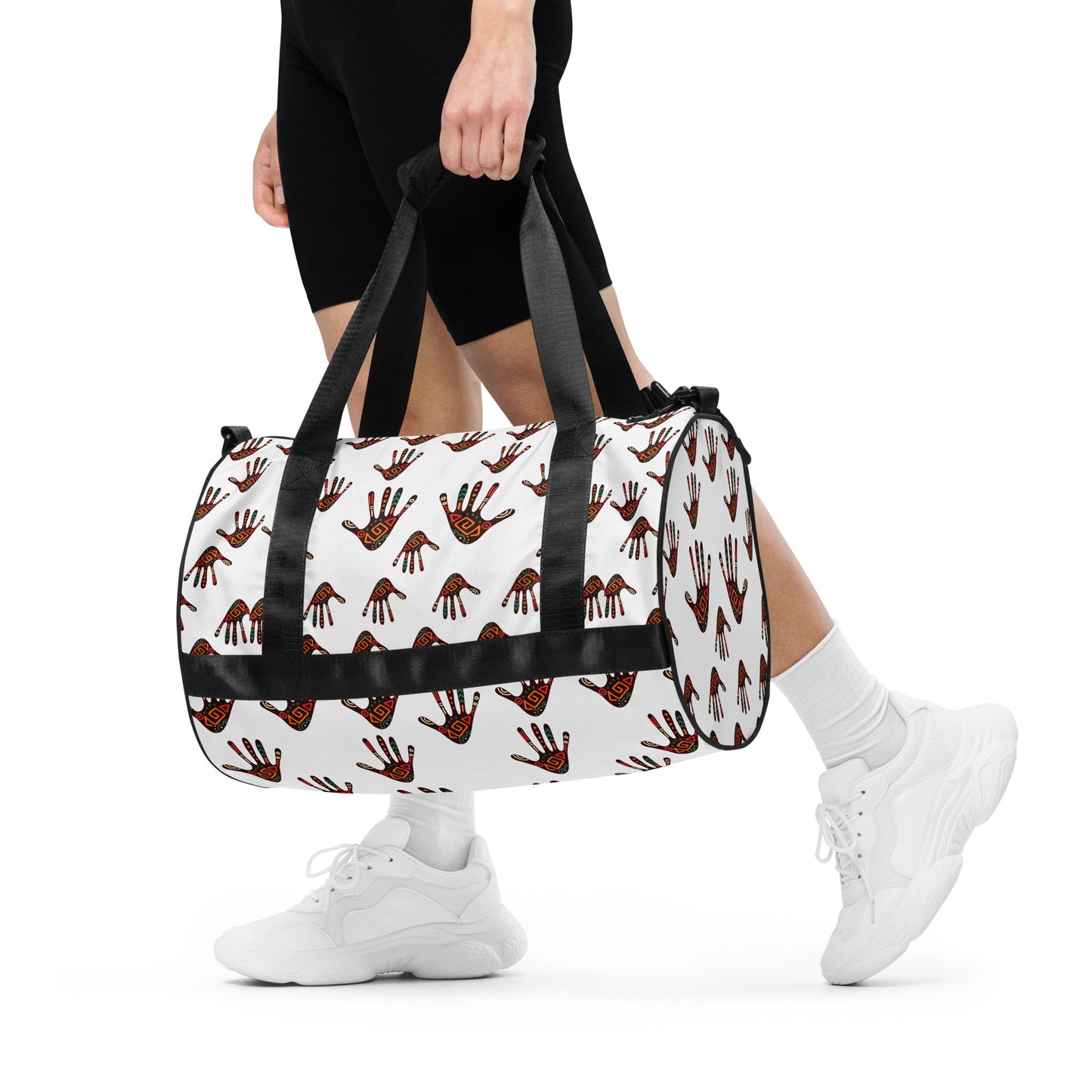 A woman holding the Duro Tribal Palm Print Overnight Gym Bag by hand, with its dual shorter straps. 