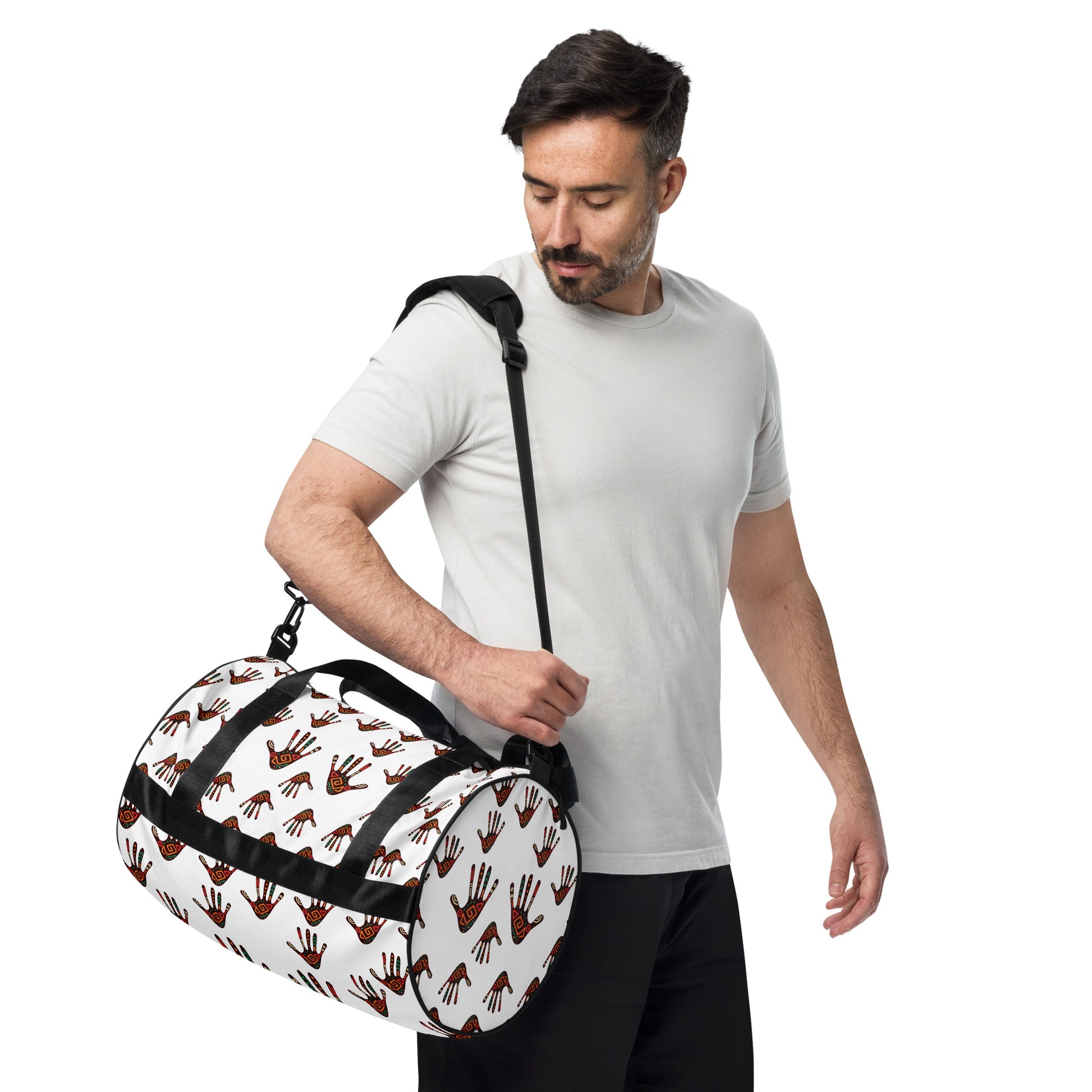 A man carrying the Duro Tribal Palm Print Overnight Gym Bag with the padded long straps on his shoulder; showcasing the circle-shaped left end and side view.