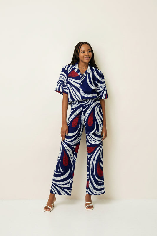 Adire-inspired navy blue and white swirl print unisex button shirt, oversized fit, worn by a dark-skinned woman with long braids,front view, juneteenth collection