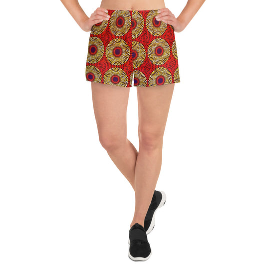 A woman wearing Rekiana African print athletic shorts with a geometric pattern in red, black, and yellow.