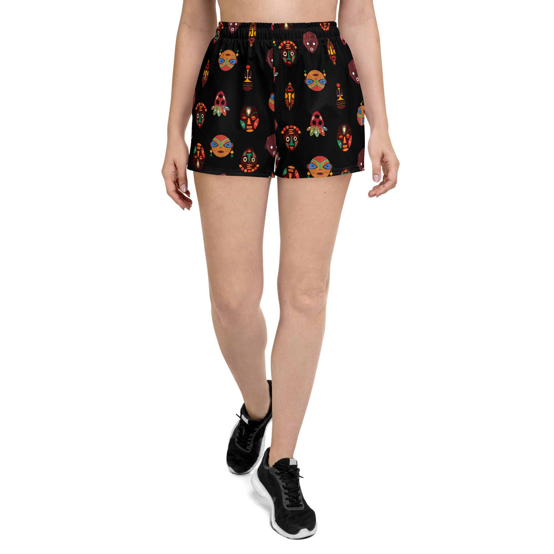 A pair of women's recycled athletic shorts with a vibrant tribal mask print, featuring a flat white drawstring, mesh side pockets, and a mid-rise fit.