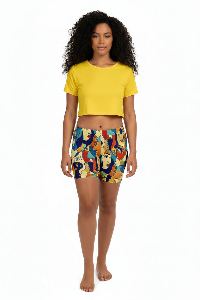 Woman wearing a yellow crop top and colorful patterned shorts on a white background