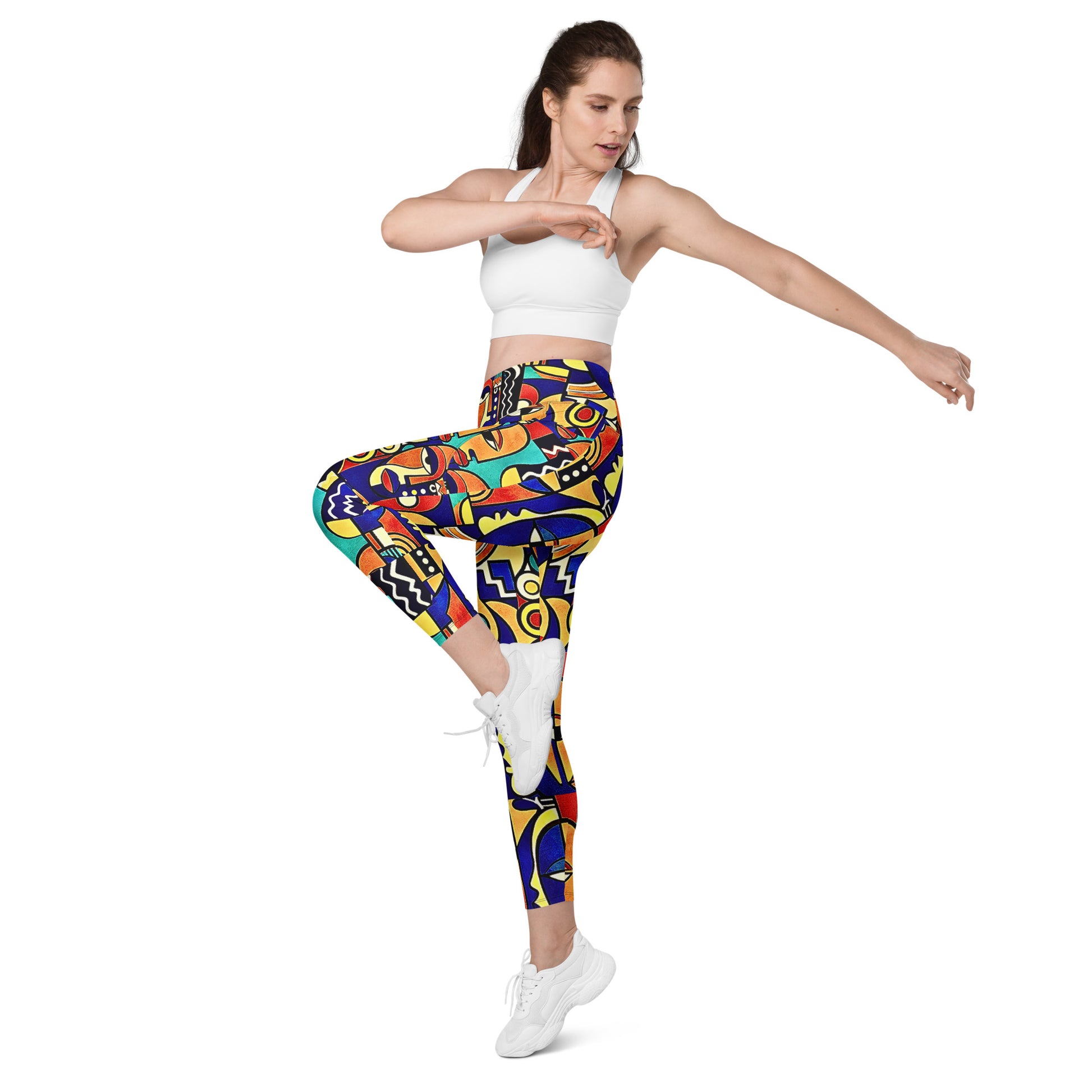 Woman wearing colorful patterned Asake oge leggings and a white sports bra on a white background