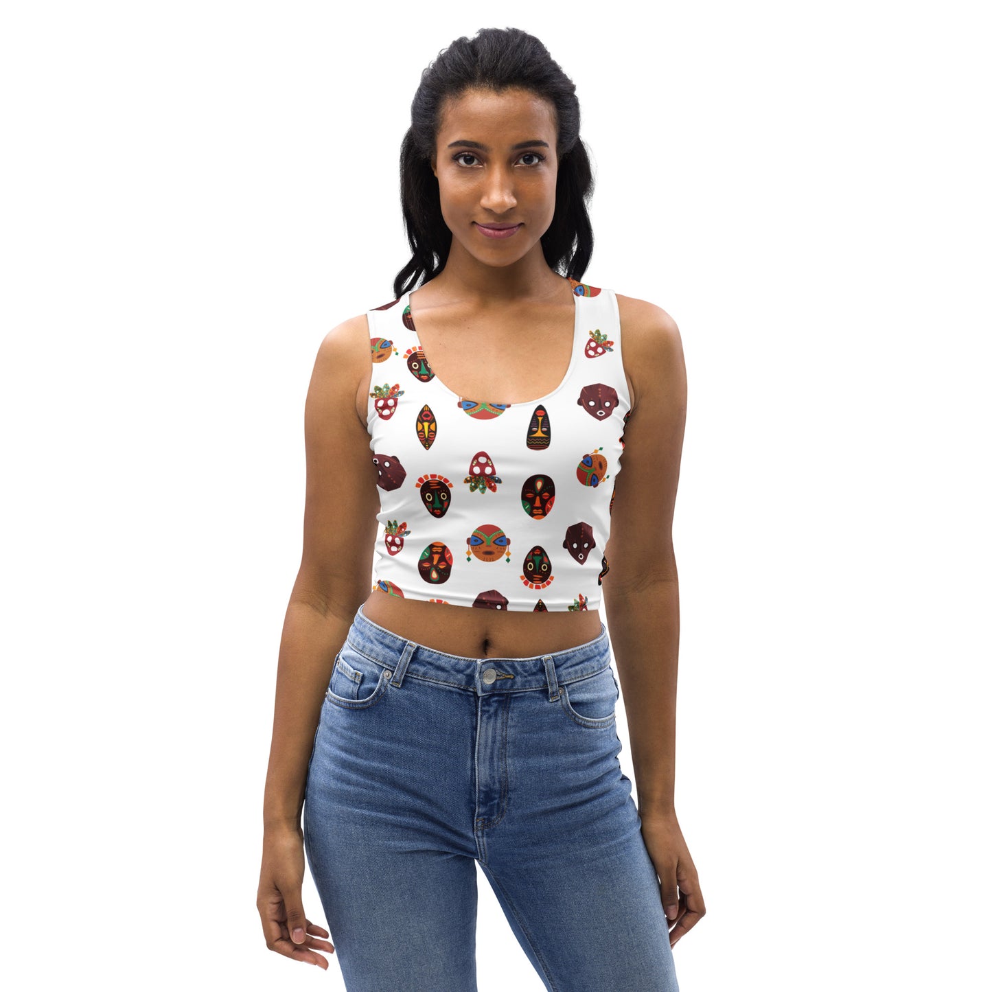 A woman wearing a white crop tank top with a colorful geometric tribal mask pattern.