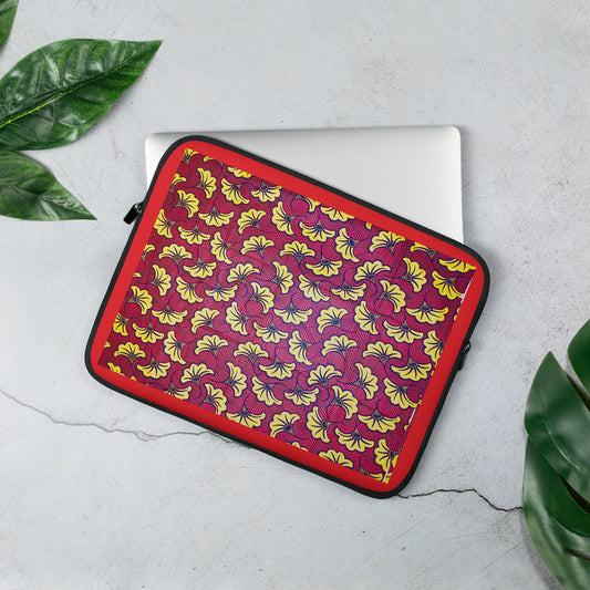 A 13 inch laptop sleeve with a floral African print pattern in the colors red, yellow, and black; displayed on a laptop.